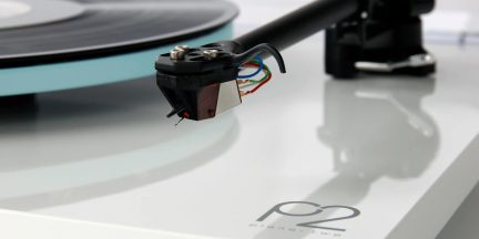 White Rega Planar 2 turntable, close-up of tonearm and cartridge with colored cables