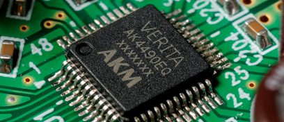Green printed circuit board with a rectangular black electronic component bearing the inscription "AKM 4396VF", close-up view