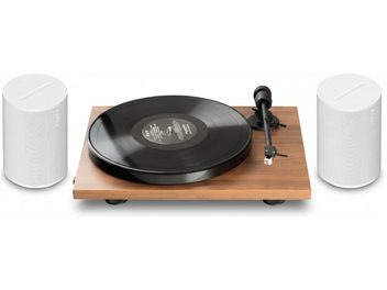 Vinylspelare med träfinish, svart skiva, tonarm och två vita Sonos-högtalare