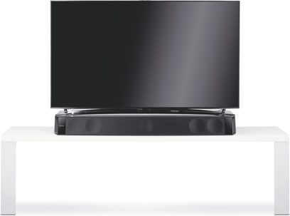 Barre de son Focal Dimension Noir, vue de face, posée sur un meuble blanc, avec un écran de télévision noir au-dessus