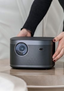 XGIMI Horizon Pro 4K sort videoprojektor set forfra, objektiv og sensor, hånd holder toppen