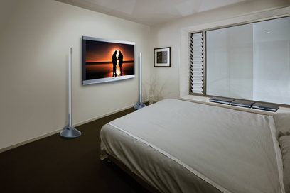 Silhuet af par, der holder hånd i solnedgangen ved en sø, vist på et tv i et hotelværelse