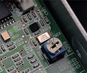 Grønt printplade med elektroniske komponenter, A6984 kvartsoscillator og blå elektrolytisk kondensator, tæt på visning