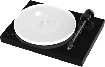 Pro-Ject X1 pladespiller i piano sort, set oppefra, hvid rund pladespiller, sort tonarm, på en rektangulær, blanklakeret sort base
