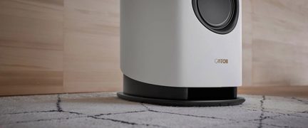 Subwoofer Canton bianco finitura opaca, base nera circolare, vista ravvicinata su tappeto a motivi geometrici