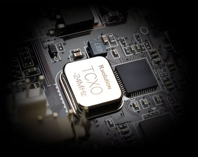 TCXO oscilátor R-volution 24 MHz na černé elektronické desce, detailní záběr na plošný spoj