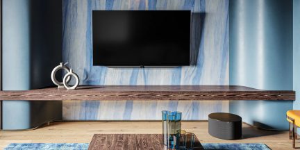 Schwarzer Flachbildfernseher an der Wand über einer Holzkonsole in einem Wohnzimmer in Blautönen