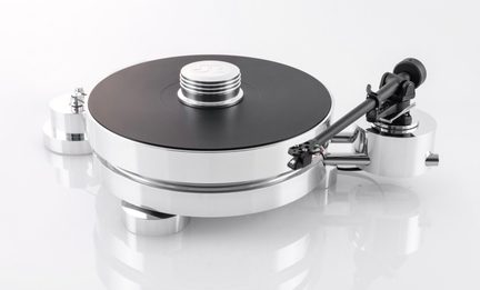Prato de vinil em metal polido prateado, bandeja circular preta com um peso prateado no topo, braço de leitura preto à direita e cilindro metálico lateral esquerdo, vista em perspectiva três-quartos frontal ligeiramente em plongée