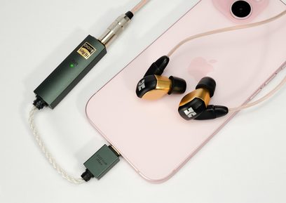 Bærbar lydkonverter iFi Audio GO link Max, set ovenfra, flettet kabel, sorte og gyldne hovedtelefoner, lyserød smartphone