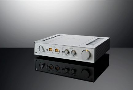 Brushed aluminum audio amplifier, front panel with knobs and jacks, front view on a solid gray background