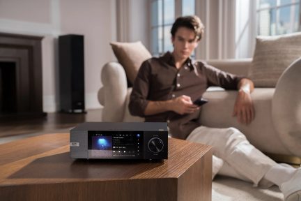 Black Eversolo audio network player with color screen and volume knob on a living room table