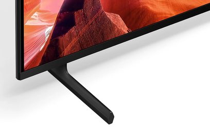 Sony KD65X80L højdefinitions-tv, set fra en vinkel, sort skærm, tynd kant, sort metalstativ, flad overflade