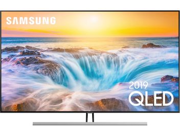 Televizor Samsung QE55Q85R zobrazující tyrkysovou vlnu, která se valí na pláž při oranžovém západu slunce