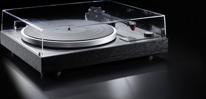 Hi-Fi-Plattenspieler Dual CS 518 von Dual, schwarze Zarge mit strukturiertem Holzfurnier, silbernes Aluminiumteller, geschlossenem transparentem Acryl-Deckel und schwarzem Tonarm mit rotem Tonabnehmer, aus vorderer Dreiviertelansicht