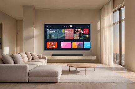 Vægmonteret fladskærms-tv med multimedieinterface i en moderne beige stue, stort panoramavindue til højre