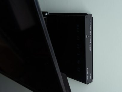 Ampli для домашнього кінотеатру MRX-SLM чорного кольору, вид збоку, кріпиться до стіни, гладка поверхня, білий текст, 4 видимі гвинти, сусідній чорний екран