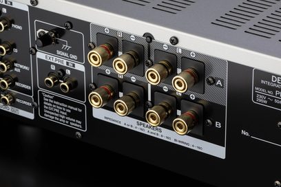 Denon PMA-1700NE sølv hi-fi stereoanlegg, nærbilde bakfra av de forgylte RCA-lydkontaktene og skrueterminaler for høyttalertilkobling