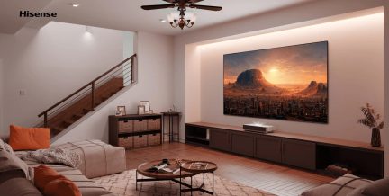 Moderne stue med beige sofa, orange puder, rundt sofabord, TV-møbel, vægmonteret skærm, trappe i træ, loftsventilator