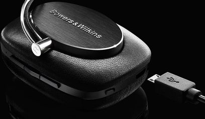 Otwarte słuchawki hi-fi Bowers & Wilkins P5 Wireless czarne, widok z lewej strony pod kątem trzech czwartych, leżące na czarnym skórzanym etui, kabel USB