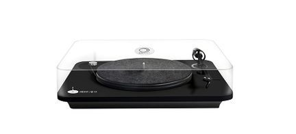 Black vinyl turntable with tonearm, rotating platter, control knobs, and transparent plexiglass dust cover