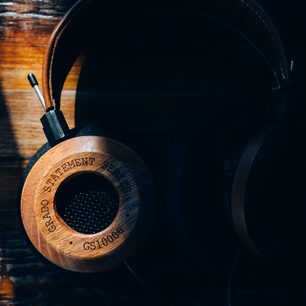 Åben hi-fi hovedtelefon Grado GS1000e i træ, set fra venstre profil, placeret på en træholder indgraveret med "Statement"