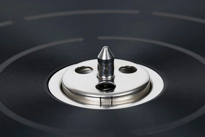 Thorens TD 124 DD plak çalar, fırçalanmış metalden yapılmış dairesel plaka ve krom kaplı konik merkez eksenine odaklanmış yakın çekim