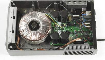 Cyrus PSX-R sidabrinės spalvos atvirojo maitinimo šaltinio viršutinis vaizdas iš vidaus su toroidinio transformatoriaus, spausdintinių plokščių ir elektroninių komponentų vaizdais