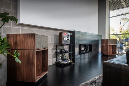 Pair of walnut-finish hi-fi speakers, displayed in a modern living room with vintage audio equipment