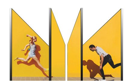 Twee mensen dansen voor gele panelen, profiel aanzicht in medium shot tegen een witte achtergrond