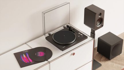 Sort Kanto-pladespiller med gennemsigtigt låg, to sorte højttalere og subwoofer