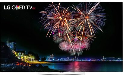 LG OLED 4K TV viser et farverigt fyrværkeri over en oplyst by ved vandet om natten