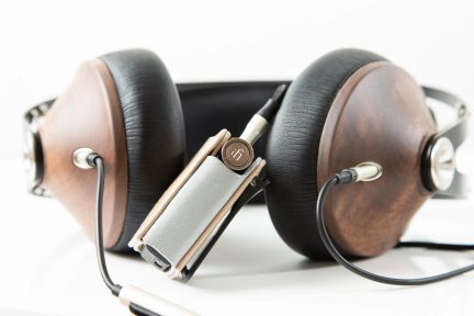 Over-ear-hovedtelefoner med ørekopper i træ og sorte læderpuder, jackkabler, sølvfarvet bærbart kabinet med drejeknap, close-up