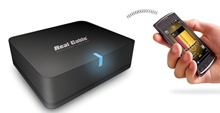 Boîtier noir mat en plastique Real Cable avec témoin LED bleu, vue de trois-quarts, à côté d’un smartphone tenu en main