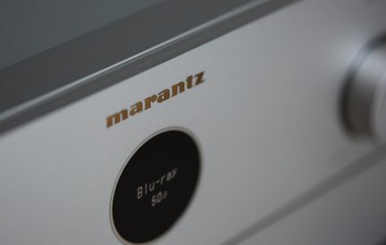 Zilverkleurige aluminium voorzijde van een Marantz-versterker, schuin gezien, zwart cirkelvormig scherm Blu-ray 50.0, draaiknop rechts