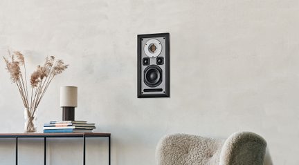 Cassa acustica da parete rettangolare nera e grigia in metallo e plastica, vista frontale con tweeter a nastro circolare argentato, due piccoli altoparlanti quadrati, un woofer rotondo nero e fessura bass-reflex inferiore