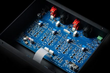 Scheda elettronica audio blu con componenti e connettori rossi e neri, vista dall'alto in un involucro nero