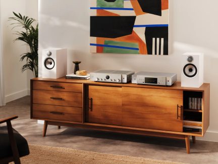 Bílé regálové reproduktory a stříbrná hi-fi sestava na nízké dřevěné komodě v moderním obývacím pokoji