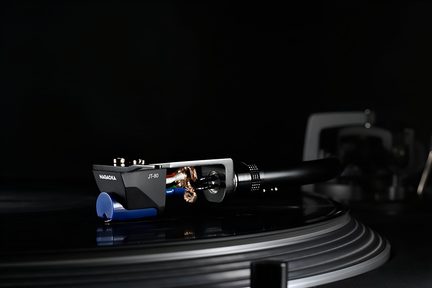 Černá fonokapsle s modrou špičkou a stříbrným kovovým krytem, boční detailní záběr na černý raménko položené na rýhovaném vinylovém talíři