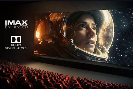 Sala kinowa, widok skośny, czarne i czerwone fotele, gigantyczny ekran z metalicznym astronautą w hełmie, logotypy IMAX i Dolby