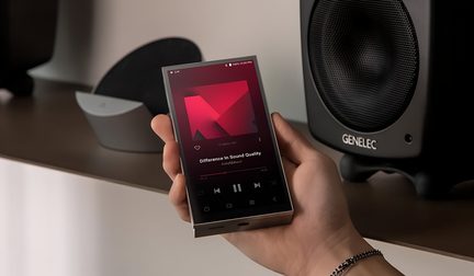 Widok z trzech czwartych, przenośny odtwarzacz audio w kształcie prostokąta, wykonany ze szczotkowanego srebrnego metalu, o wyraźnych krawędziach i dużym czarnym ekranie dotykowym zajmującym niemal całą przednią powierzchnię, trzymany w jednej dłoni