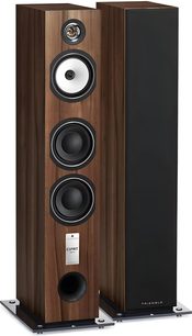 Cassa acustica a colonna Triangle Antal serie EZ in finitura castagno con impiallacciatura in legno marrone, vista a tre quarti che mostra una coppia: una senza griglia rivela tweeter a tromba, midrange bianco, due woofer neri e condotto bass-reflex frontale, mentre l’altra presenta un frontale in tessuto nero; entrambe poggiano su basi metalliche.