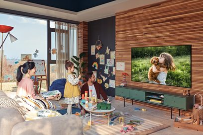 Moderní obývací pokoj s dětmi, které kreslí, hrají si a dívají se na televizi, dřevěným nábytkem, velkými okny a barevnou dekorací