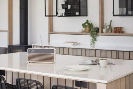 Beige digitalradio med riflet front og teleskopantenne på en køkkenø