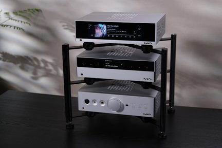 Silverfärgad hi-fi-anläggning i tre delar på svart rack, nätverksspelare med skärm, DAC och hörlursförstärkare