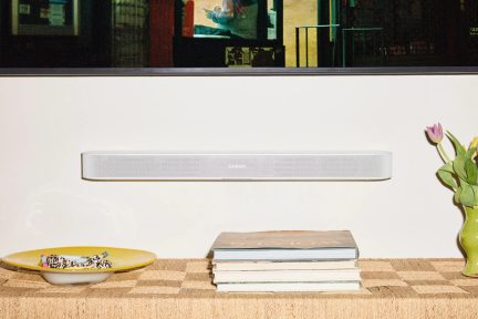 Soundbar Sonos bianca fissata alla parete sopra una console con libri e vaso fiorito