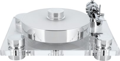 Hi-Fi vinylový přehrávač Transrotor Bellini RB330 ve stříbrné a průhledné barvě, pohled zepředu, kruhový kovový talíř s leštěným povrchem a přítlačným kotoučem, průhledný akrylový podstavec na čtyřech válcových nohách a chromovaný raménko na pravé straně