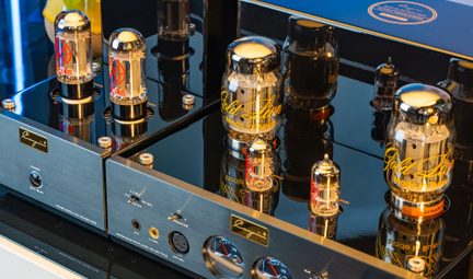 Amplificatore a valvole nero lucido, frontalino in metallo spazzolato, grandi valvole in vetro, prese jack e XLR, vista a tre quarti