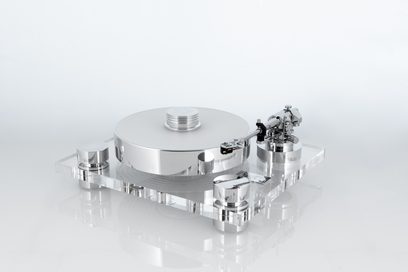 Hi-Fi vinylová platina Transrotor Bellini RB330 ve stříbrné barvě, kovový talíř a rameno s leštěným povrchem namontované na tlustém průhledném akrylovém obdélníkovém podstavci, pohled z levé přední perspektivy