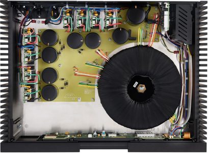 Indvendigt syn af en åben Naim NPX 300 lydforstærker, der viser de elektroniske komponenter på et grønt printplade og en stor sort toroidaltransformator