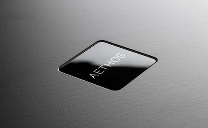 Ampli hi-fi stéréo Rega Aethos Noir, vue de dessus en gros plan sur la façade en verre avec logo blanc et texte "AETHOS"